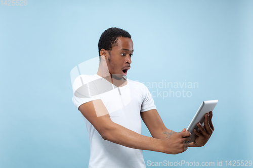 Image of Half-length close up portrait of young man on blue background.