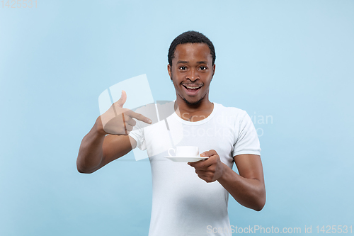 Image of Half-length close up portrait of young man on blue background.