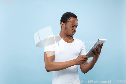 Image of Half-length close up portrait of young man on blue background.