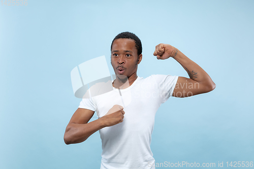 Image of Half-length close up portrait of young man on blue background.