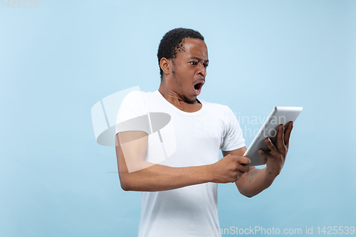 Image of Half-length close up portrait of young man on blue background.