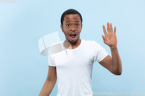 Image of Half-length close up portrait of young man on blue background.