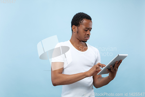 Image of Half-length close up portrait of young man on blue background.