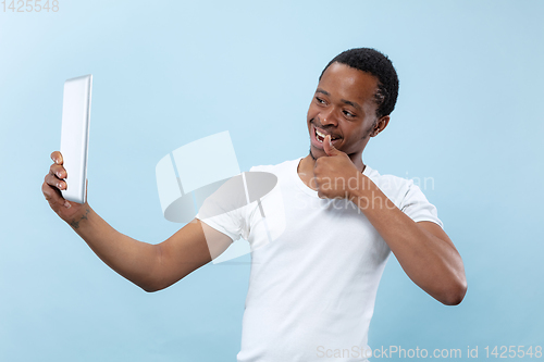 Image of Half-length close up portrait of young man on blue background.