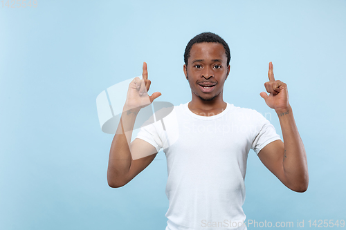 Image of Half-length close up portrait of young man on blue background.