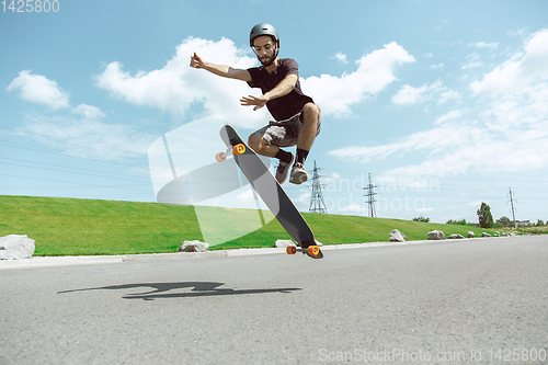 Image of Skateboarder doing a trick at the city\'s street in sunny day