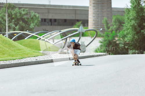 Image of Skateboarder doing a trick at the city\'s street in sunny day