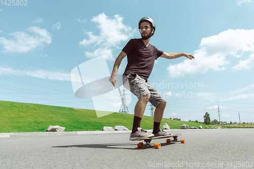 Image of Skateboarder doing a trick at the city\'s street in sunny day