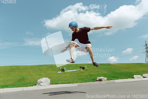 Image of Skateboarder doing a trick at the city\'s street in sunny day