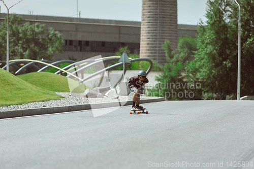 Image of Skateboarder doing a trick at the city\'s street in sunny day