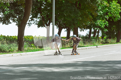 Image of Skateboarders doing a trick at the city\'s street in sunny day