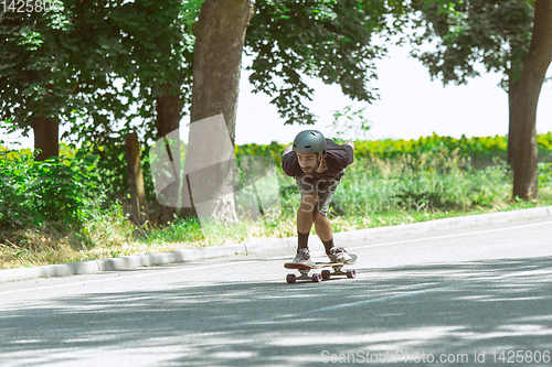 Image of Skateboarder doing a trick at the city\'s street in sunny day