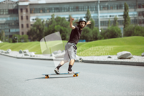 Image of Skateboarder doing a trick at the city\'s street in sunny day