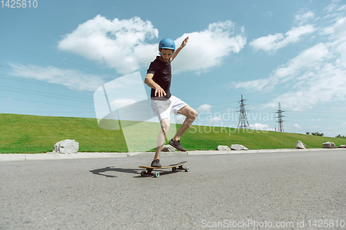 Image of Skateboarder doing a trick at the city\'s street in sunny day