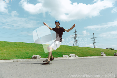 Image of Skateboarder doing a trick at the city\'s street in sunny day