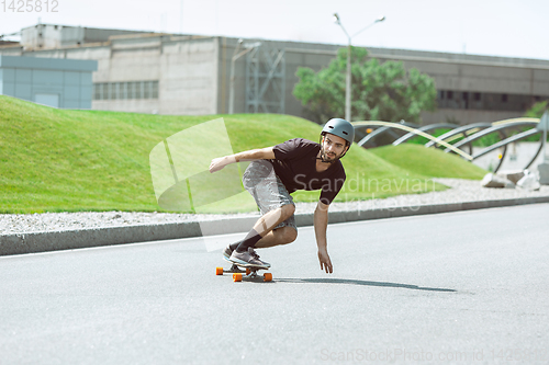 Image of Skateboarder doing a trick at the city\'s street in sunny day