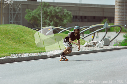 Image of Skateboarder doing a trick at the city\'s street in sunny day
