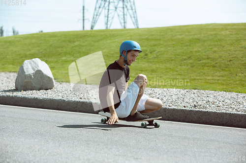 Image of Skateboarder doing a trick at the city\'s street in sunny day