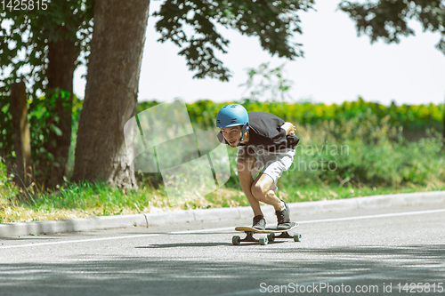 Image of Skateboarder doing a trick at the city\'s street in sunny day