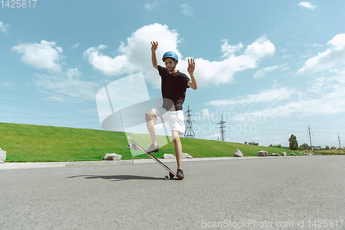 Image of Skateboarder doing a trick at the city\'s street in sunny day