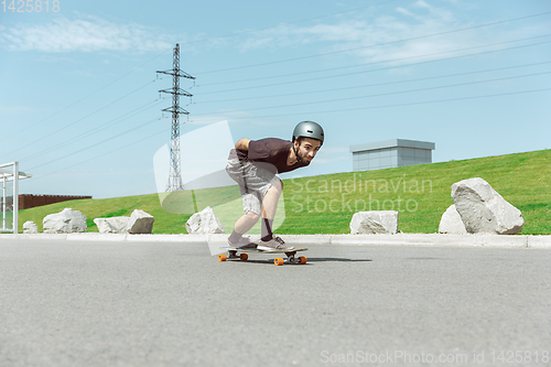 Image of Skateboarder doing a trick at the city\'s street in sunny day