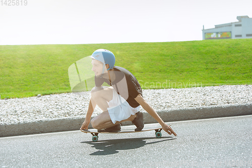 Image of Skateboarder doing a trick at the city\'s street in sunny day