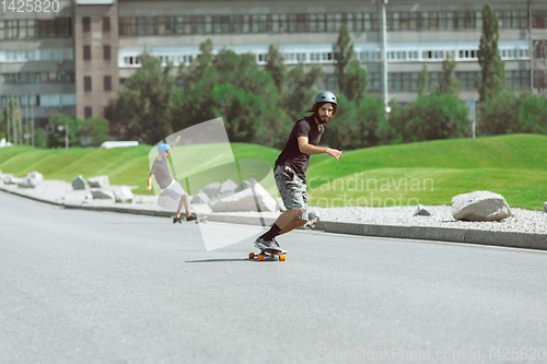 Image of Skateboarders doing a trick at the city\'s street in sunny day