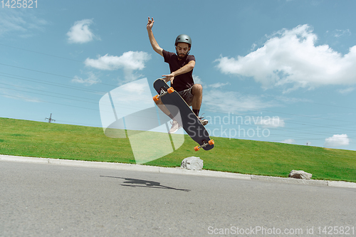 Image of Skateboarder doing a trick at the city\'s street in sunny day