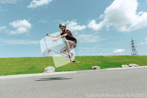 Image of Skateboarder doing a trick at the city\'s street in sunny day