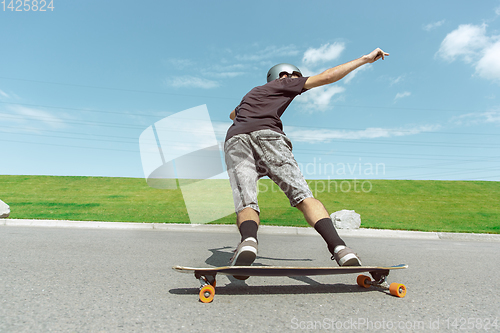 Image of Skateboarder doing a trick at the city\'s street in sunny day