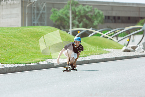 Image of Skateboarder doing a trick at the city\'s street in sunny day