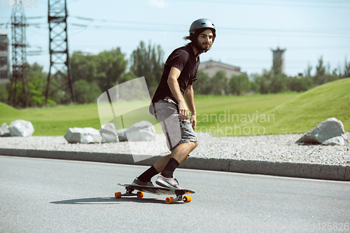 Image of Skateboarder doing a trick at the city\'s street in sunny day