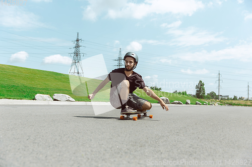 Image of Skateboarder doing a trick at the city\'s street in sunny day