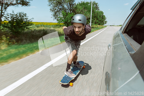 Image of Skateboarder doing a trick at the city\'s street in sunny day