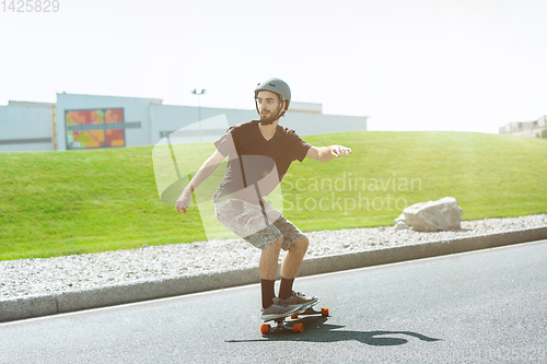 Image of Skateboarder doing a trick at the city\'s street in sunny day