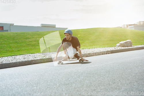 Image of Skateboarder doing a trick at the city\'s street in sunny day