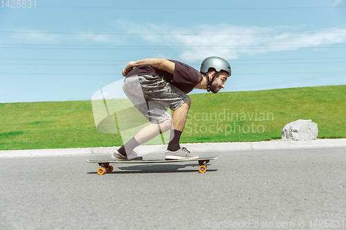 Image of Skateboarder doing a trick at the city\'s street in sunny day