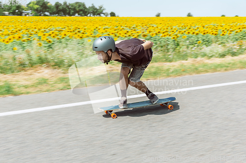 Image of Skateboarder doing a trick at the city\'s street in sunny day