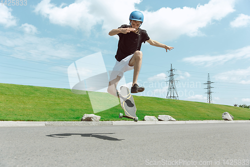Image of Skateboarder doing a trick at the city\'s street in sunny day