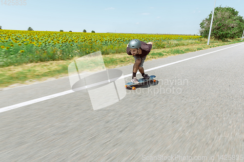 Image of Skateboarder doing a trick at the city\'s street in sunny day