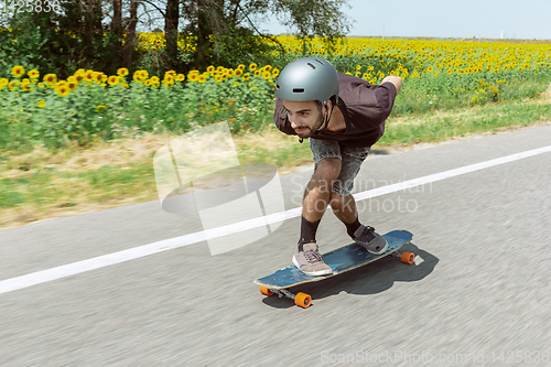 Image of Skateboarder doing a trick at the city\'s street in sunny day