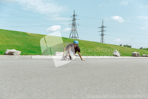 Image of Skateboarder doing a trick at the city\'s street in sunny day