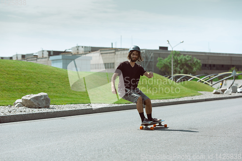 Image of Skateboarder doing a trick at the city\'s street in sunny day