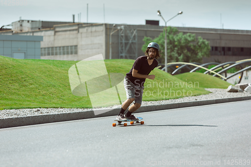 Image of Skateboarder doing a trick at the city\'s street in sunny day