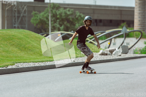Image of Skateboarder doing a trick at the city\'s street in sunny day