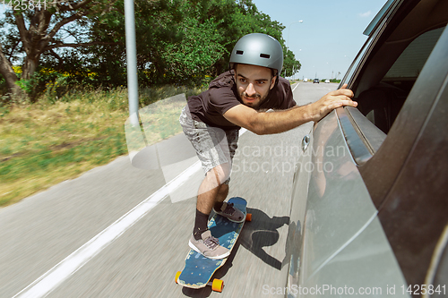 Image of Skateboarder doing a trick at the city\'s street in sunny day