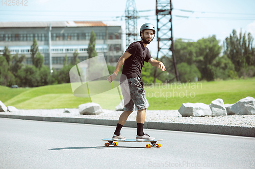 Image of Skateboarder doing a trick at the city\'s street in sunny day
