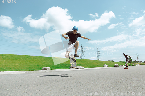 Image of Skateboarders doing a trick at the city\'s street in sunny day