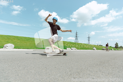 Image of Skateboarders doing a trick at the city\'s street in sunny day