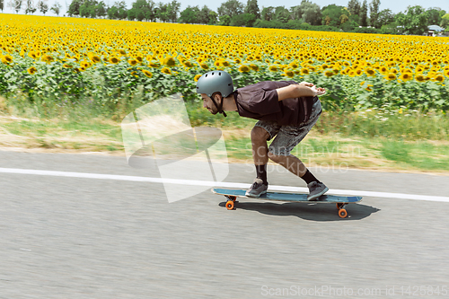 Image of Skateboarder doing a trick at the city\'s street in sunny day